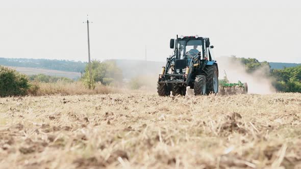 Old Tractor Plows the Field for Sowing Wheat. Cultivated Land Work in the Field. alt