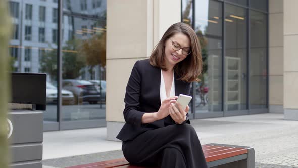 Business Woman Sitting on Bench Using Smartphone