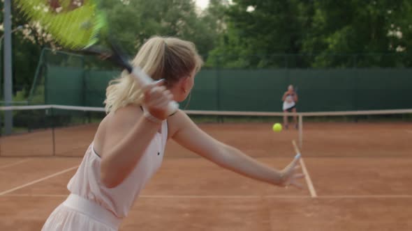 Professional Sportswoman Serving Tennis Ball to Opponent on Clay Court Outdoors Summer Background
