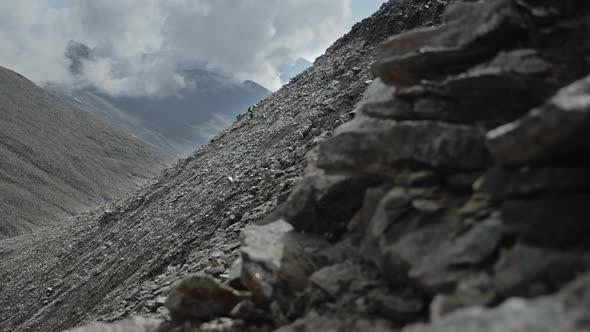 Man Climbing Under the Clouds on a Rocky Pass in a Big Mountains