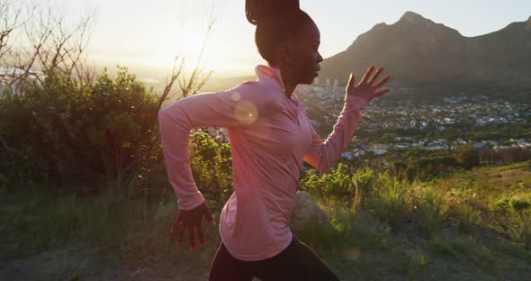 African american woman exercising outdoors running in country side during sunset alt