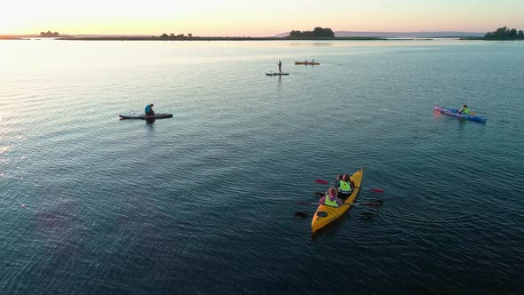 Aerial Drone Footage. A Group of Tourists Are Kayaking. Beautiful Sunrise Over River