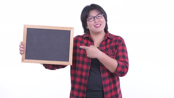 Happy Overweight Asian Hipster Woman Holding Blackboard and Giving Thumbs Up alt