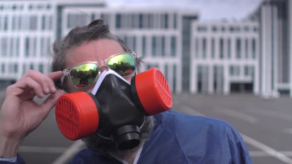 Bearded man with sunglasses, respirator and protective suit looks to sun  alt
