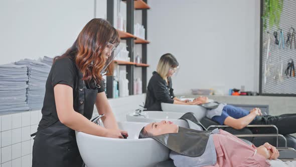 Asian young beautiful woman customer lying down on salon washing bed getting hair washed. alt