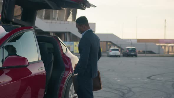 African Businessman Charging Luxury Electric Car alt