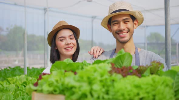 Portrait of Asian couple farmers owner working in vegetables hydroponic farm and looking at camera alt