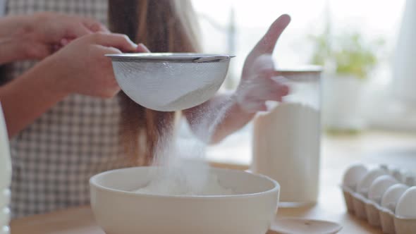 Close Up Female and Child Hands Holds Iron Sieve Sifts Wheat Flour Into Bowl Preparation of Dough alt