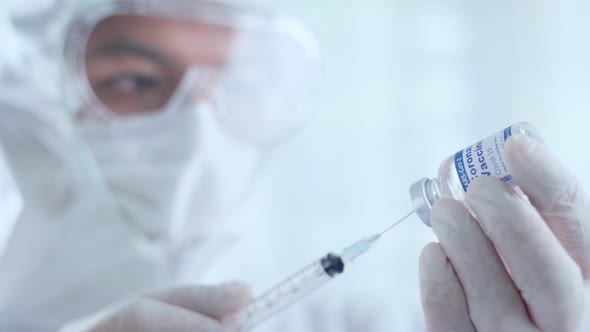 Doctor or Scientist in PPE suit draw the Covid-19 vaccine into syringe