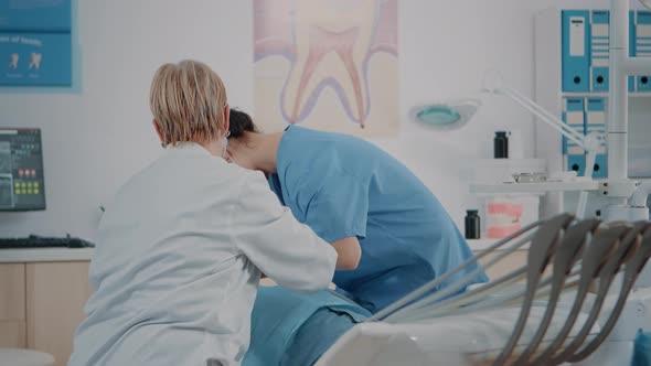 Dentist and Assistant Doing Oral Care Procedure on Patient alt