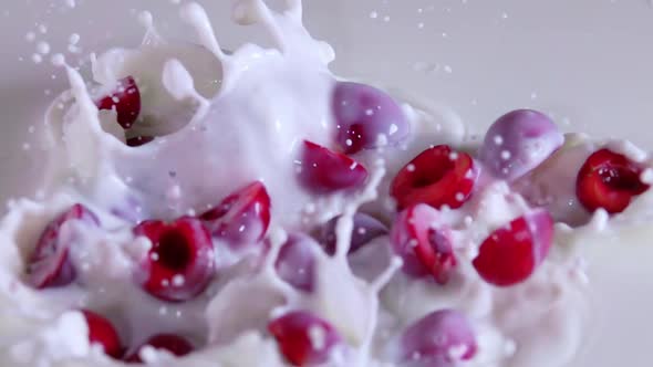 Several Halves of the Sweet Cherry Berries Fall Into the Milk