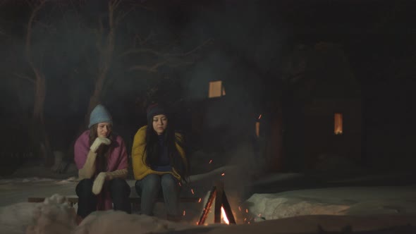 Girls spend time together near fire. alt