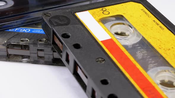 Three Vintage Audio Cassettes Rotate on White Background alt