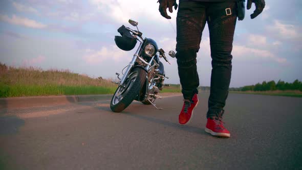 Motorcyclist Walks on the Road to His Motorcycle Chopper