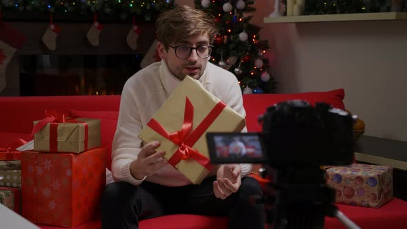 Male videoblogger filming new vlog video with professional camera at home for Christmas. alt