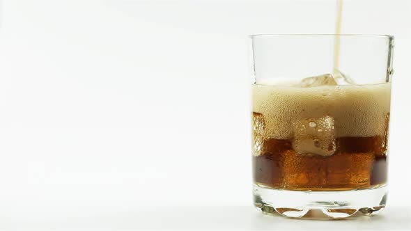 Black Soda With Ice Is Poured Into A Glass On A White Background