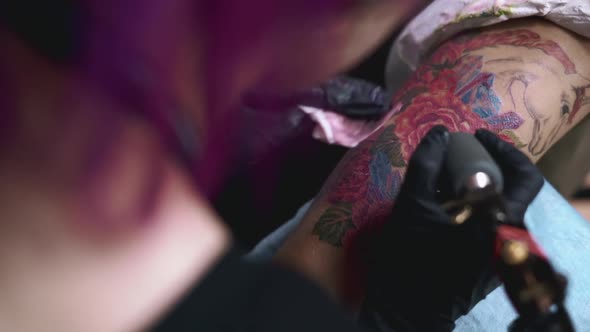 A Close-up of a Tattoo Artist Makes a Pink Unicorn on a Female Arm. Professional Tattooist Working alt