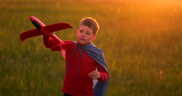 Young Boy Pilot and Runs in Field at Sunset and Playing with Plane Dreaming alt