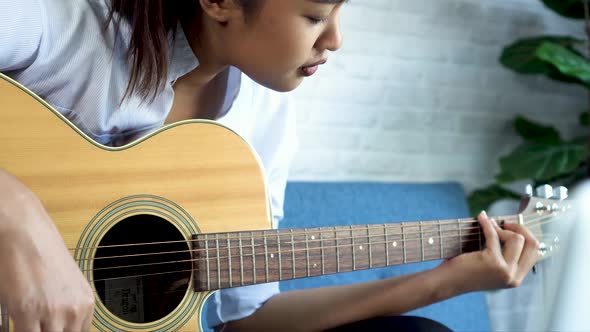 Young Asian Woman Learning How to Play Guitar on Laptop alt