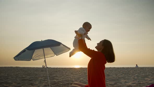 Happy Mom with Baby on Sunset Background
