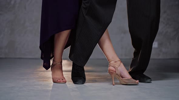 Shot of Pair of Dancers Legs Practicing Tango Element in Grey Studio