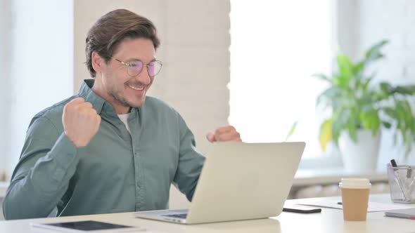 Successful Middle Aged Man Celebrating on Laptop in Office alt