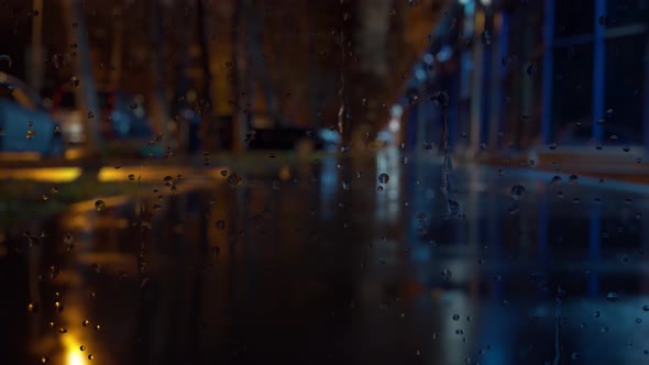 Window glass in rainy day. Bokeh night traffic lights