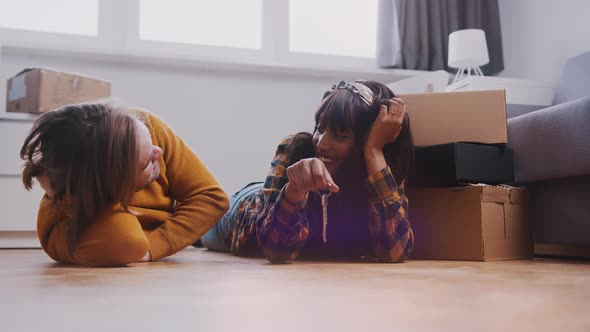 Multiracial Newlywed Couple Lying on the Floor of Their New Appartment alt