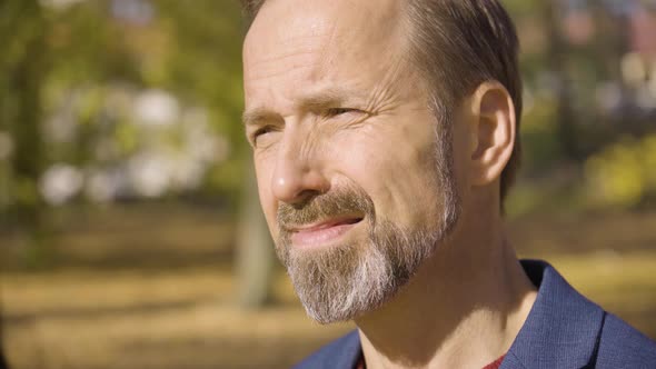 A Middleaged Handsome Caucasian Man Thinks About Something in a Park in Fall  Face Closeup