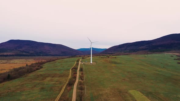 Lonely windmill in the field between Carpathian mountains of Ukraine in spring.