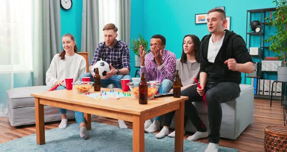 Upset Friends Watching Football and Drinking at Home Sitting on a Couch alt