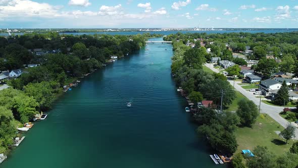 Epic Aerial of riding boat on canadian river during cloudy day with pattern on river surrounded by s alt