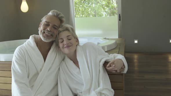 Couple in bathrobe relaxing near hot tub