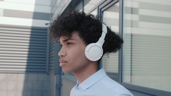 Caucasian Happy Beautiful African American Male in Headphones and Listening to Music Outdoors alt