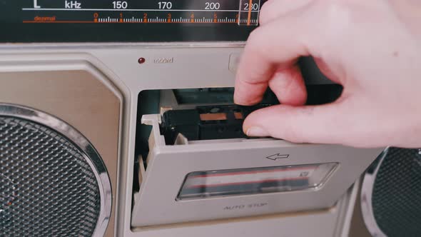 Female Hands Take Out Turn Over an Old Audio Cassette From a Tape Recorder alt