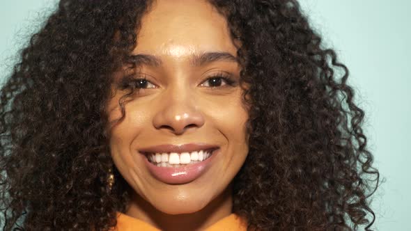 Smiling model in orange hoodie posing in studio alt