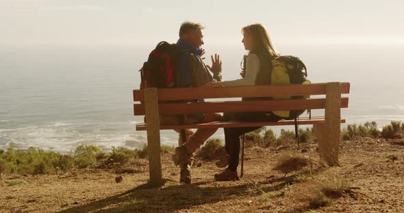 Active senior couple sitting on bench in forest alt
