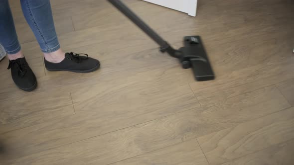 Cleaning lady vacuuming the wooden floor in the living room. House cleaning. alt