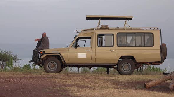 A Male Tourist Watches Africa Landscape by Safari Vehicle alt