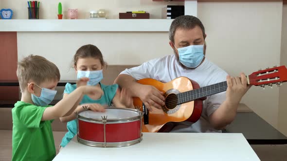 Dad and Children in Medical Masks Play Guitar and Drum . Social Distancing and Self-isolation in