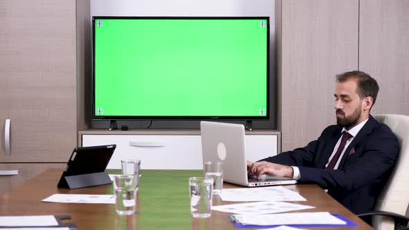 Businessman In Meeting Room Next To A Green Screen TV alt