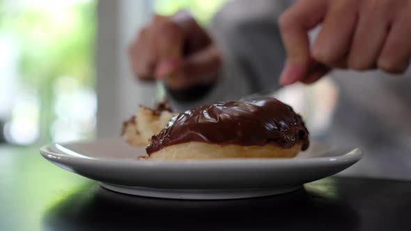 Closeup of a woman cutting and eating chocolate donut