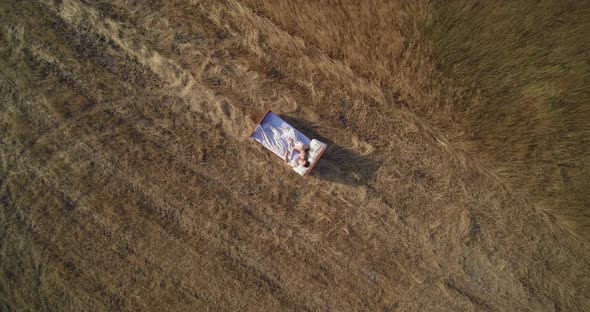 Young couple in love lies on bed in field with dry grass