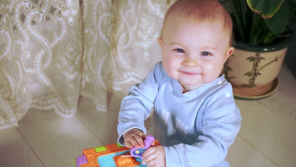 Cute Baby Sits Playing with Developmental Cube Looks at Camera and Laughs Cutely