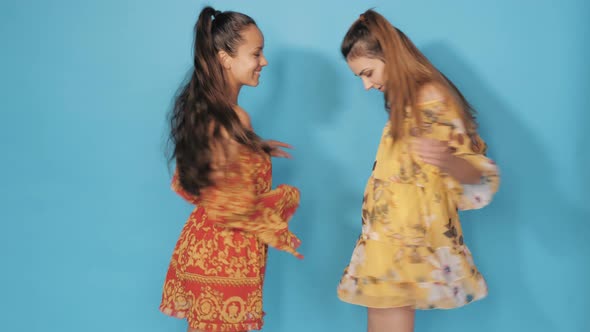 Two young beautiful smiling hipster girls in summer clothes posing in studio alt