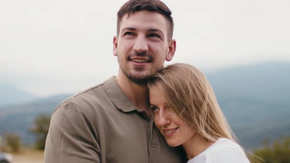 Young Loving Couple Standing and Hugging in Mountains