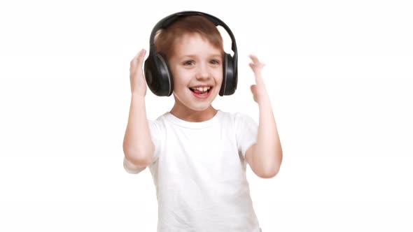 Happy Caucasian Elementaryschool Aged Boy Listening Music Through Black Big Headphones and Waving alt