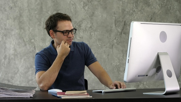Bored young man at the desk in front of computer alt