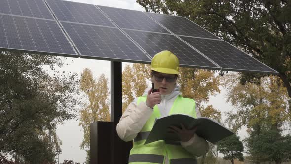 Worker inspects the solar panels and reports the information to the management alt