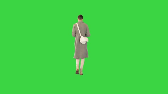 Young Woman in Stylish Clothes Walks Reading a Book on a Green Screen Chroma Key alt